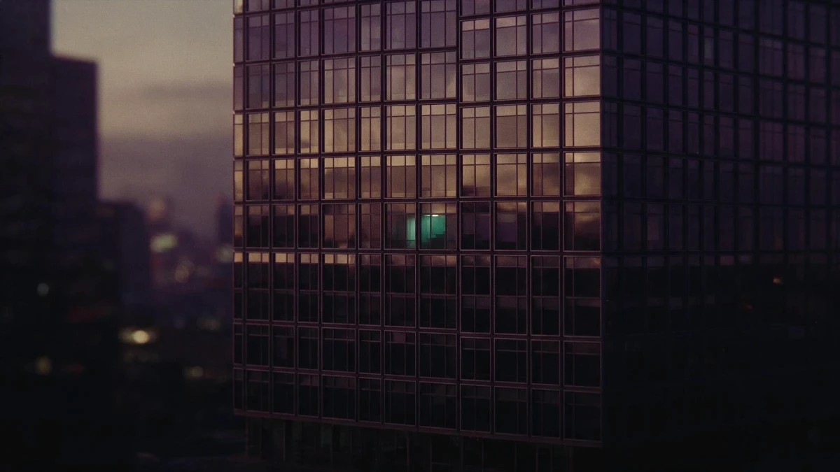 Fachada de torre corporativa com janelas idênticas e apenas uma acesa, metáfora da replicação de operações no copy trading