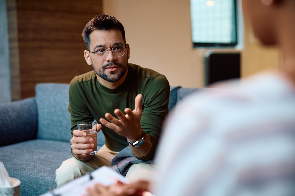 A man sat on a couch in counselling mid-conversation 