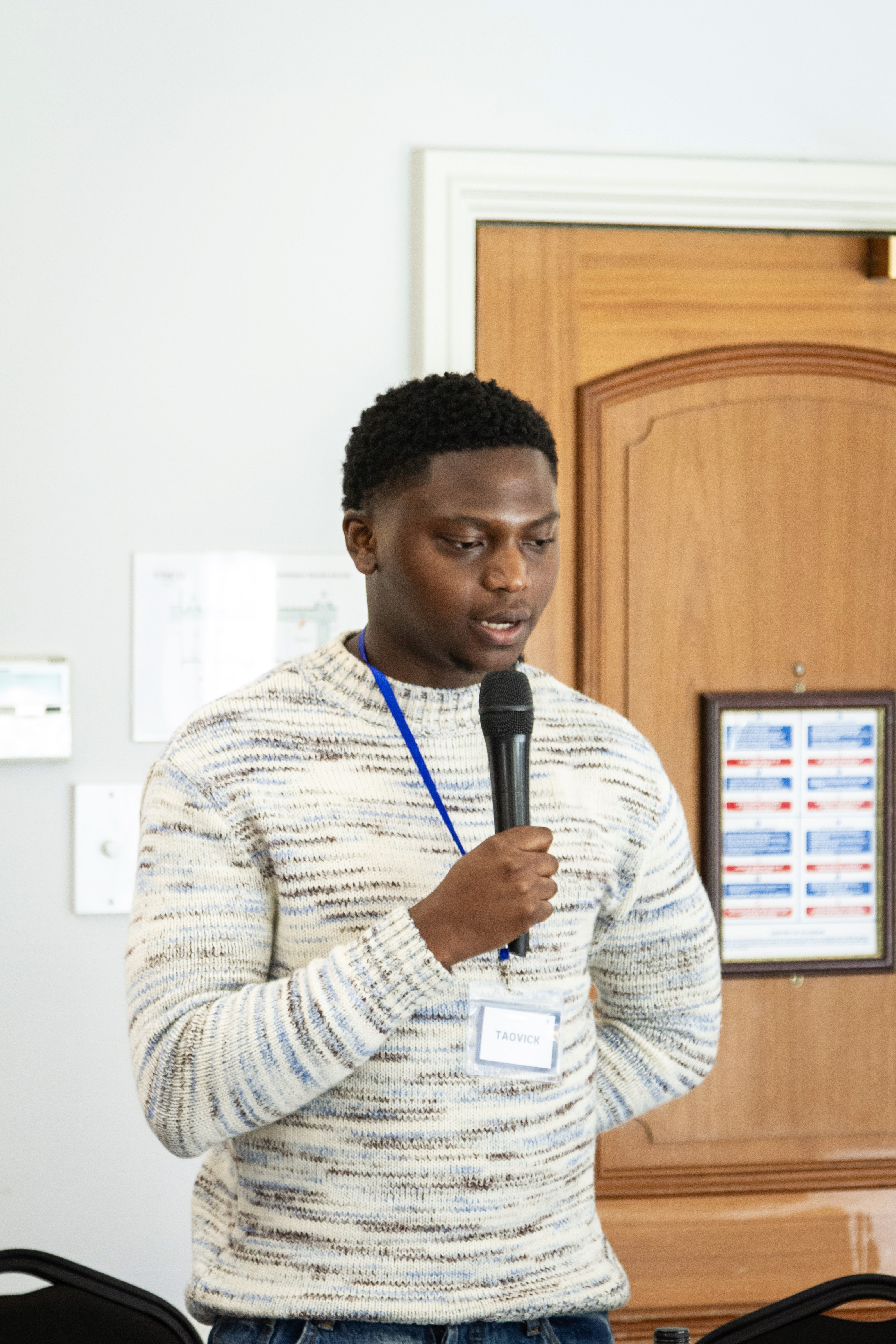Man standing and holding a microphone in a conference room. 
