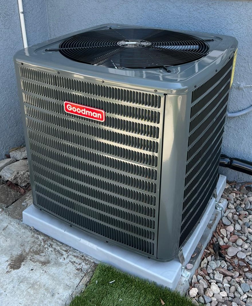 A modern house with large windows and a flat roof, surrounded by greenery against a clear blue sky.