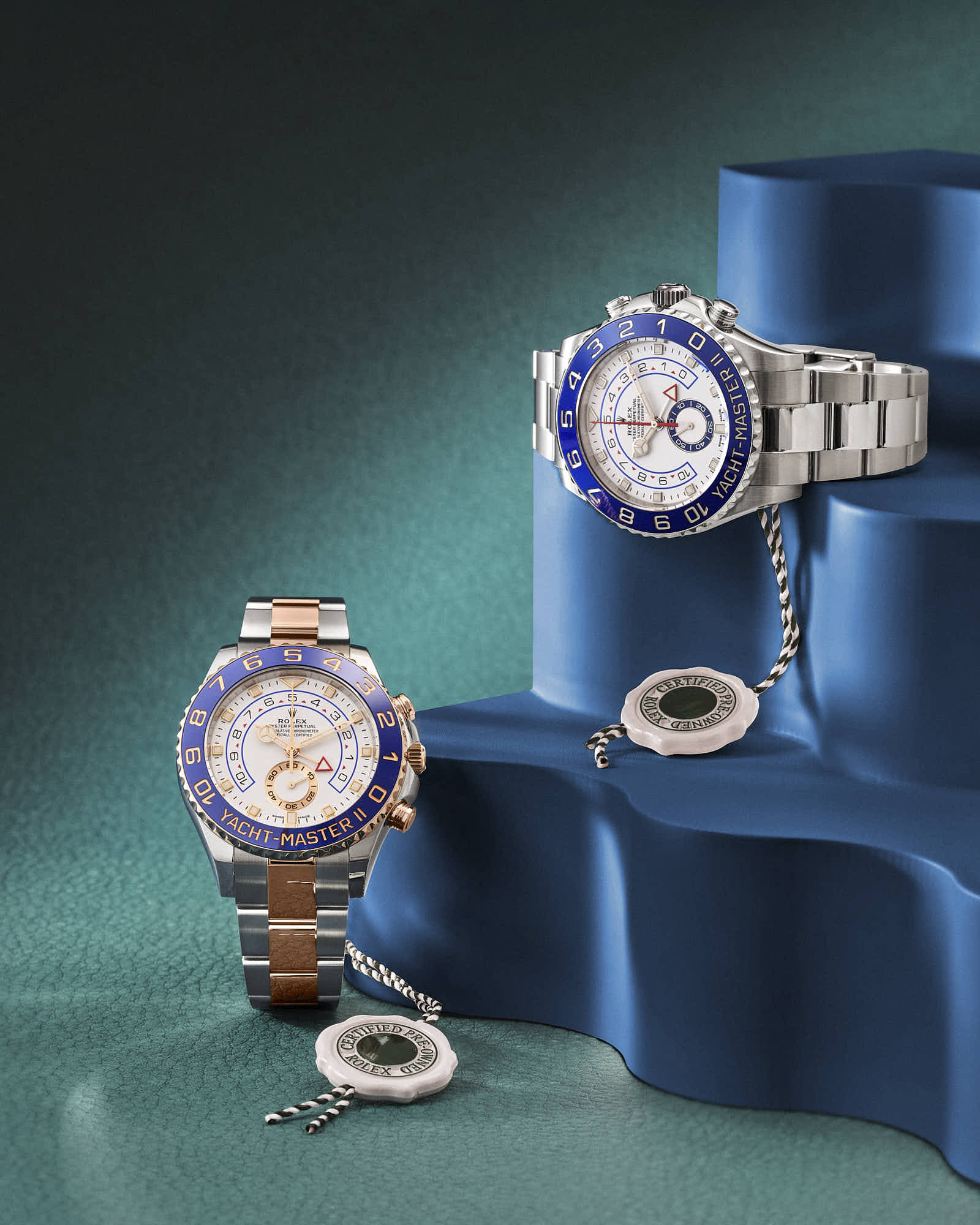 Luxury Rolex Yacht-Master watches with blue and silver accents on textured surface.