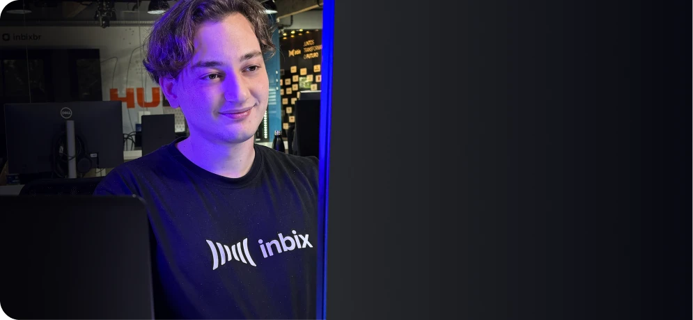 Smiling person in an Inbix T-shirt at a computer, with a tech-themed background. Represents Inbix's corporate education platform.