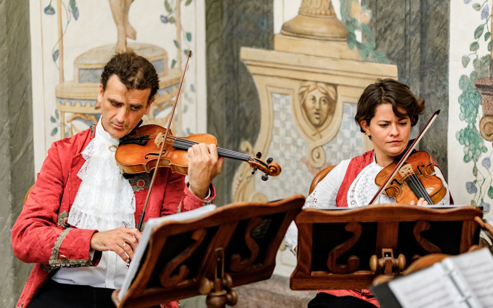 Musicians playing violins at Mozarthouse concert.