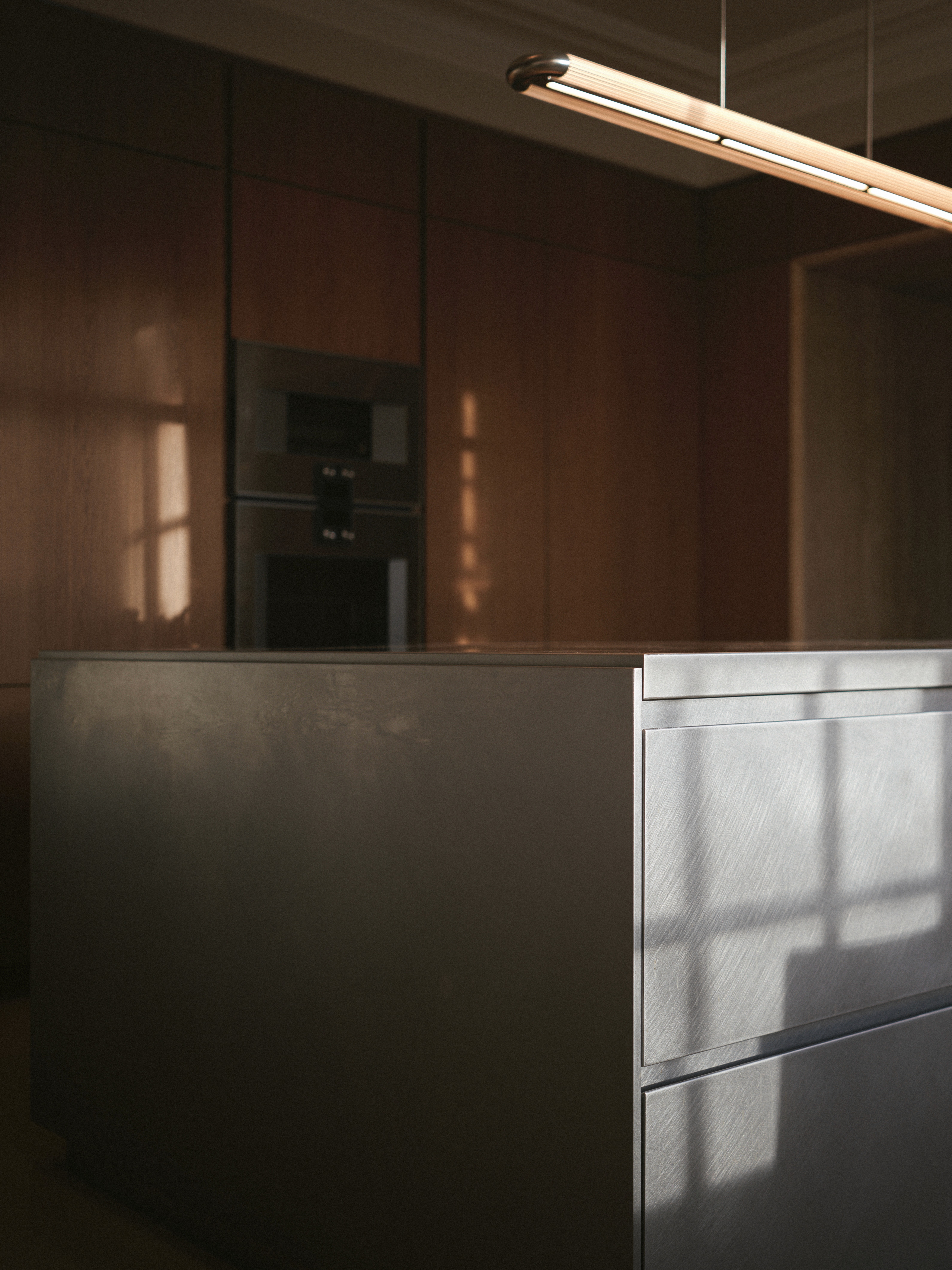 Moody Oak timber kitchen cabinetry with stainless steel island and dramatic sunlight