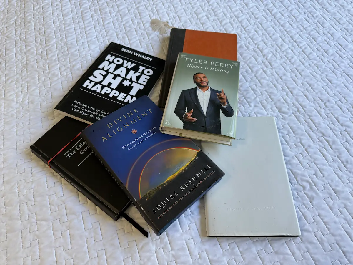 A pile of personal development and inspirational books scattered across a bed, representing daily reading and intentional mindset.