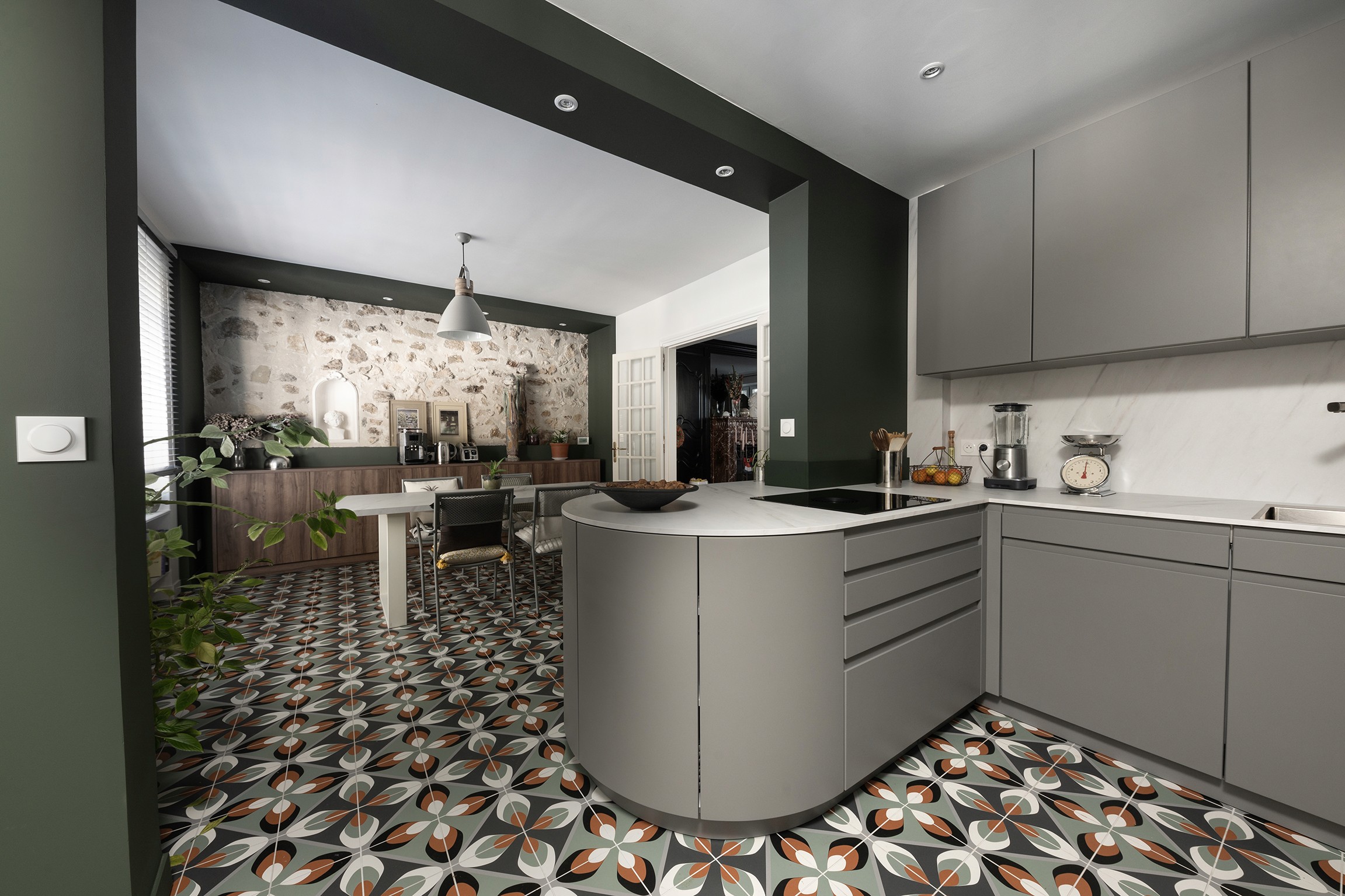 Transformation cuisine 77 avec armoires grises, comptoir marbre, murs vert olive et agencement ouvert avec coin repas, architecte d'intérieur.