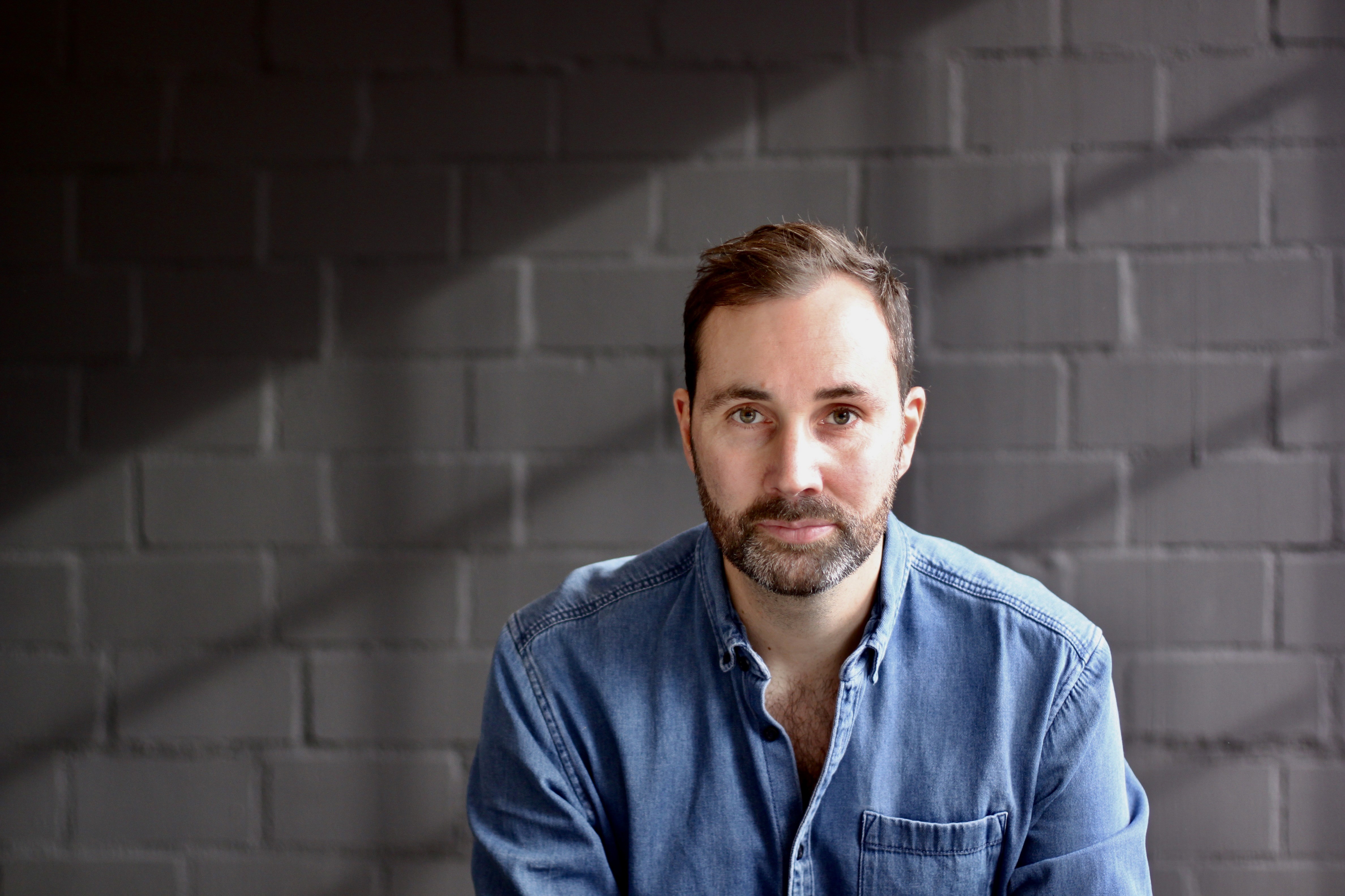 Two colleagues talking across a table with a laptop and coffee cup