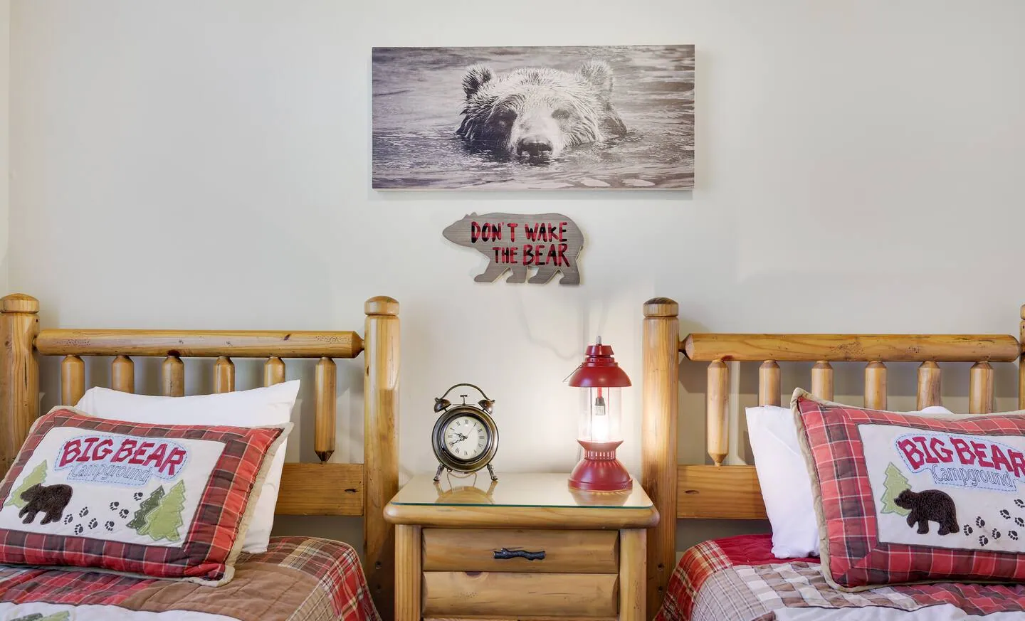 Two log twin beds with bear pillows and nightstand lamp at Mountainwoods Memories