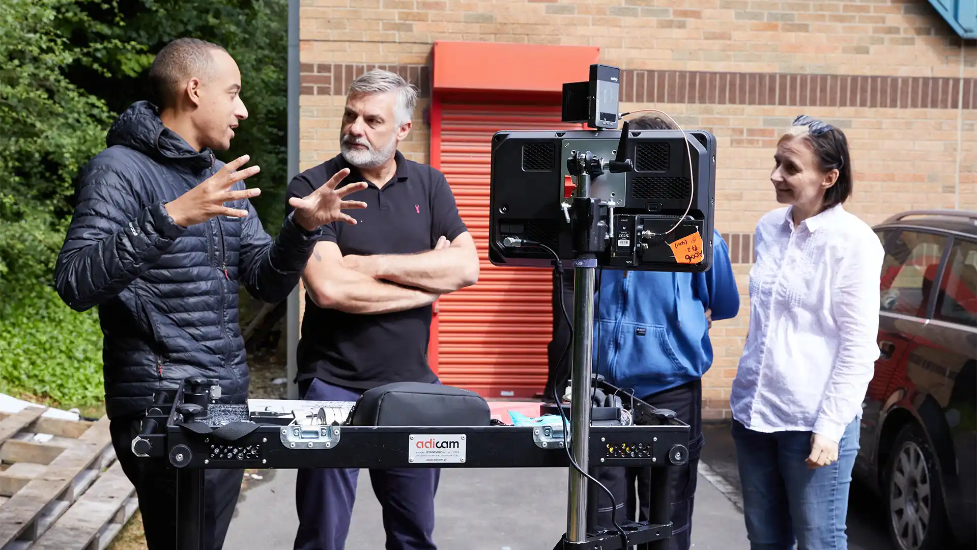Group of presenters speaking on camera during a Microsoft live broadcast, filmed against branded event graphics.