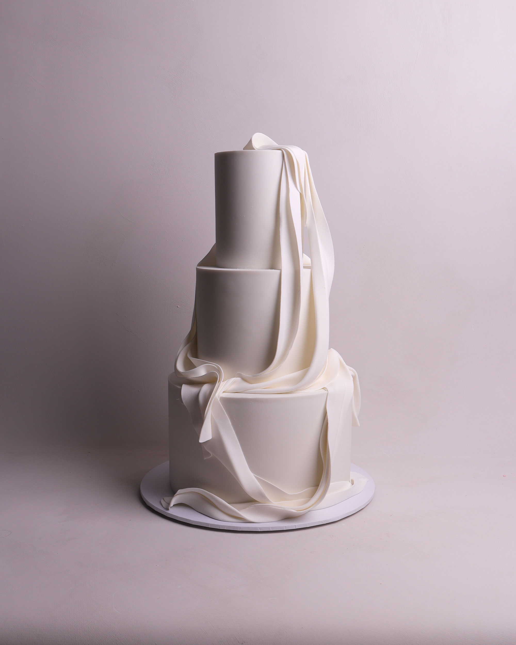 Three tier wedding cake with custom pleated texture designed to mimic folded fabric in a sculptural, minimalist style