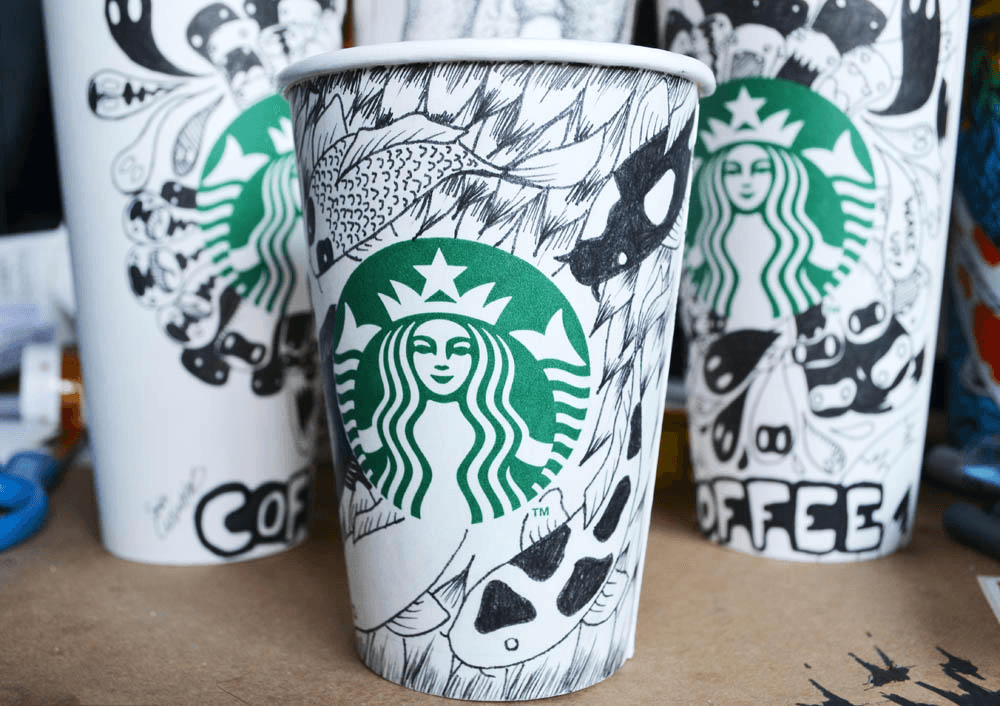 Starbucks cups with hand-painted patterns in black marker on a white cup