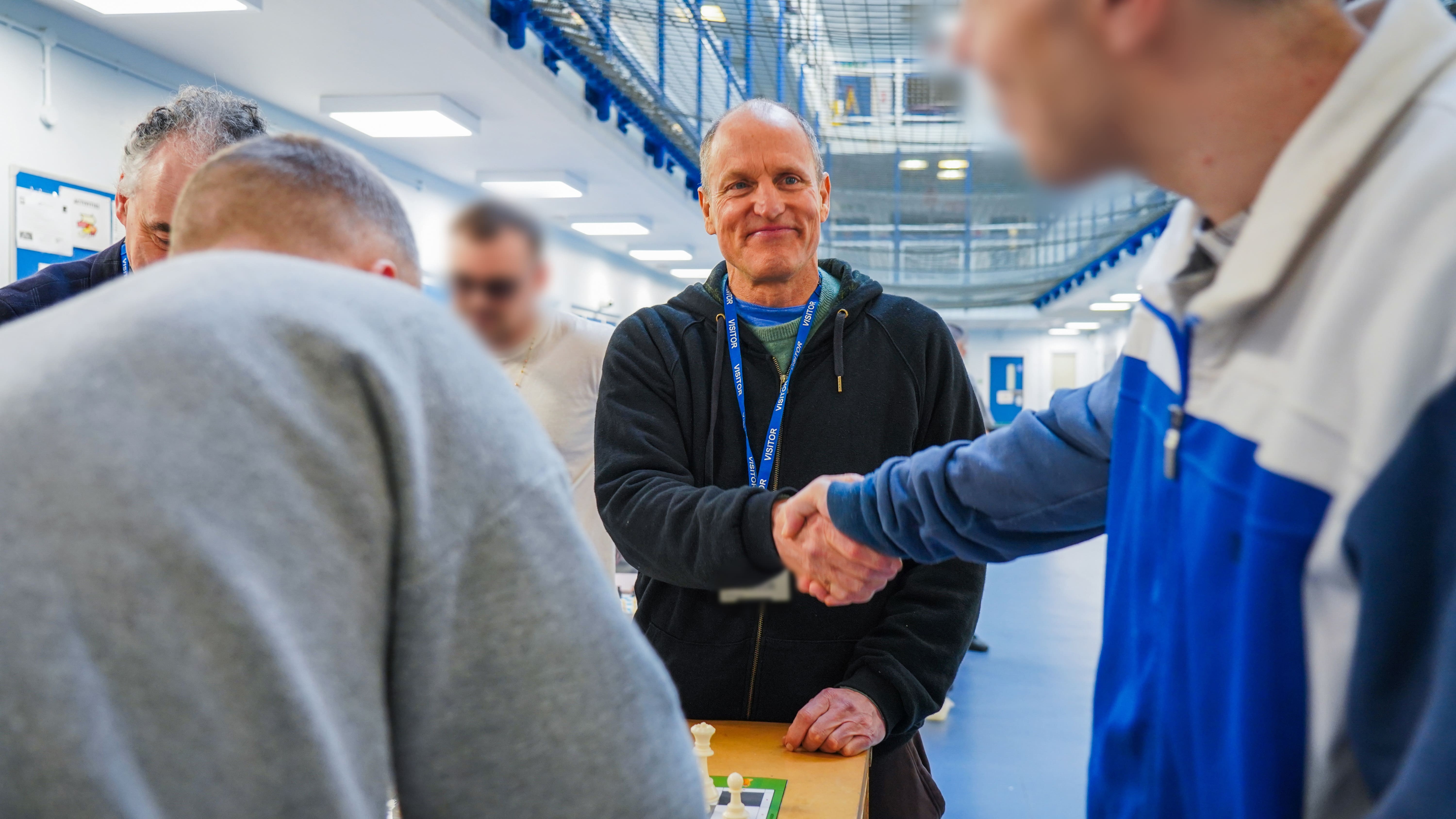 Woody Harrelson shakes hands with a prisoner as he visits the prison chess club in HMP Wormwood Scrubs in London