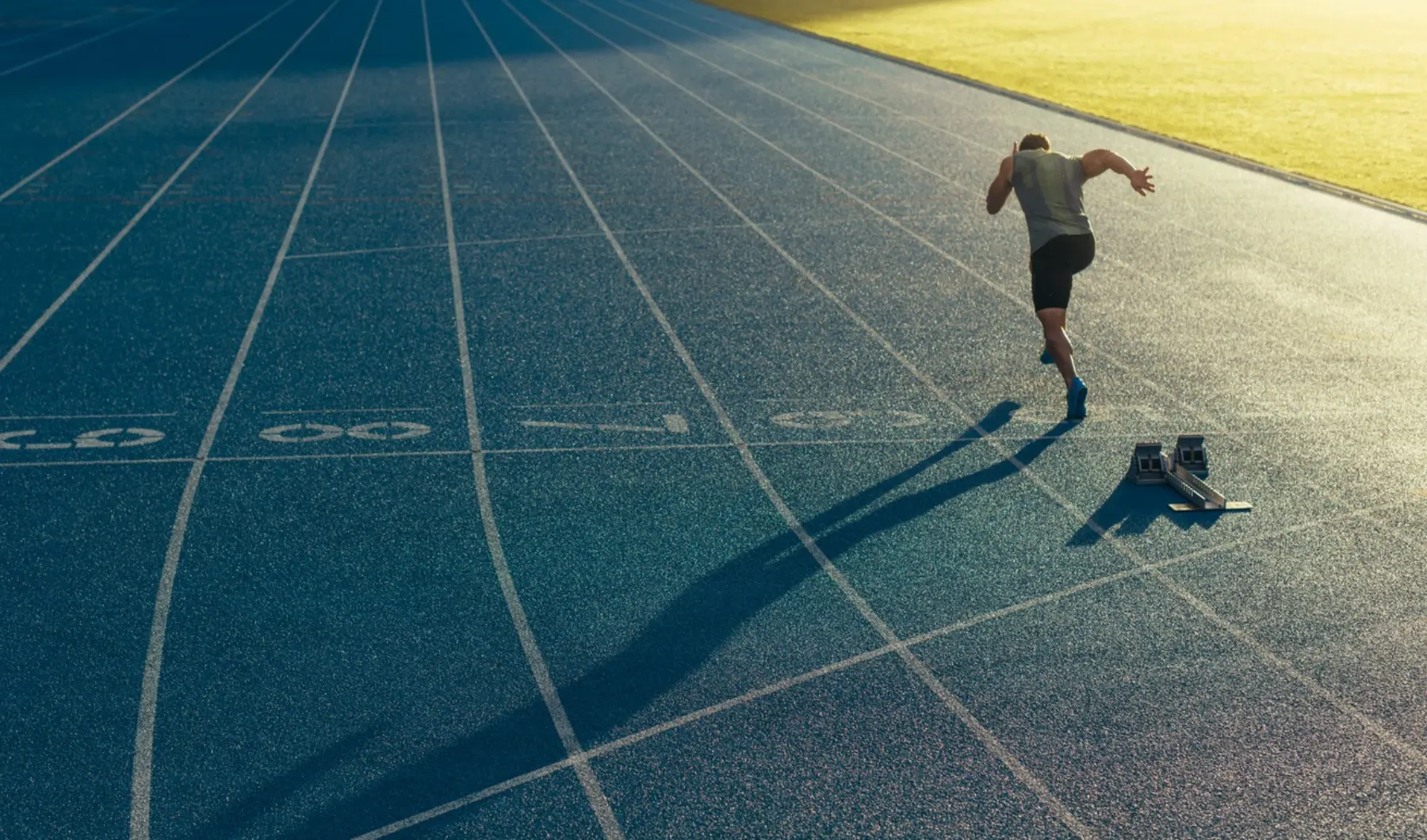 Aerial view of a sprinter leaving the starting blocks on a running track representing drive and performance
