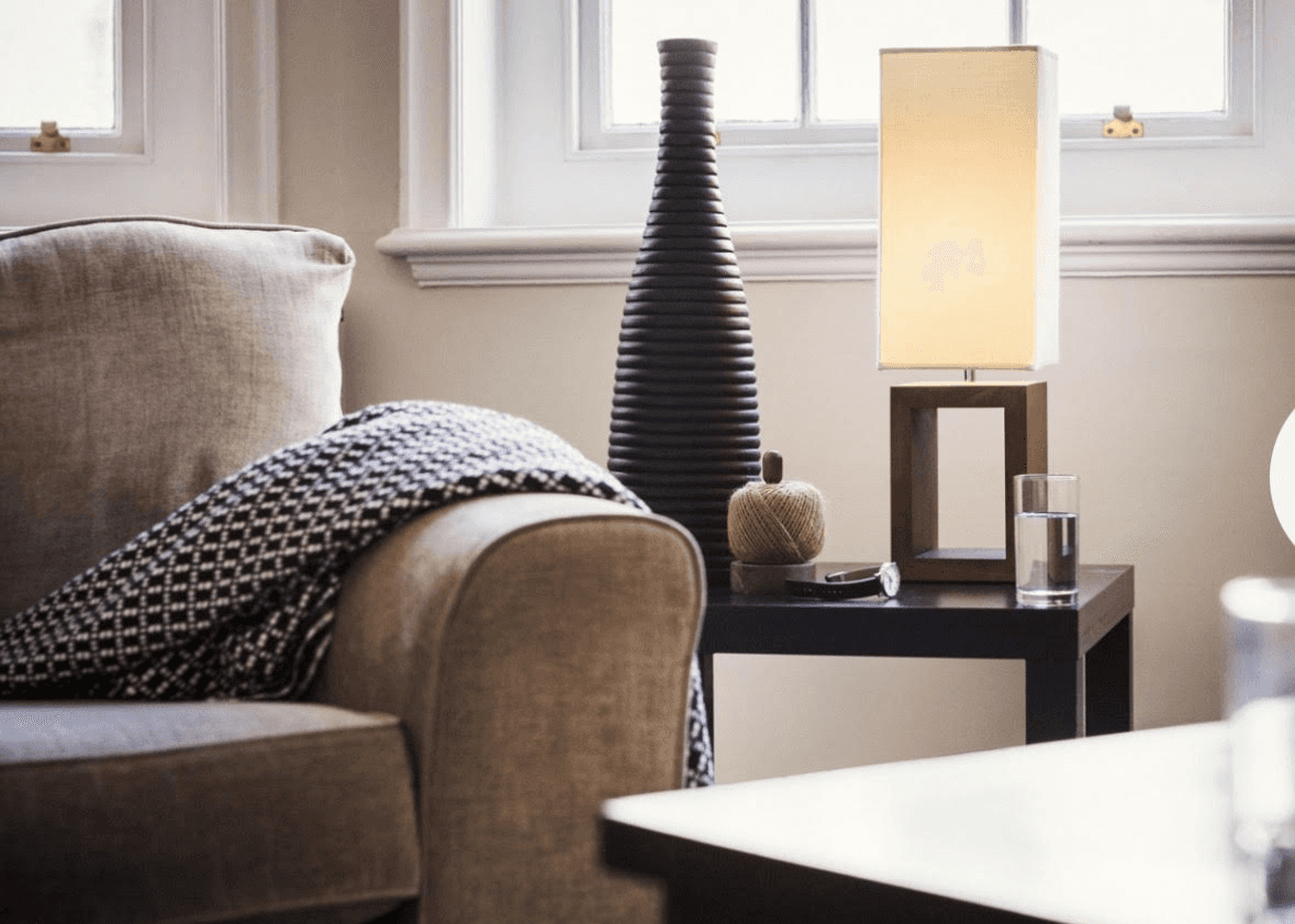 village near cliff and body of water under white clouds