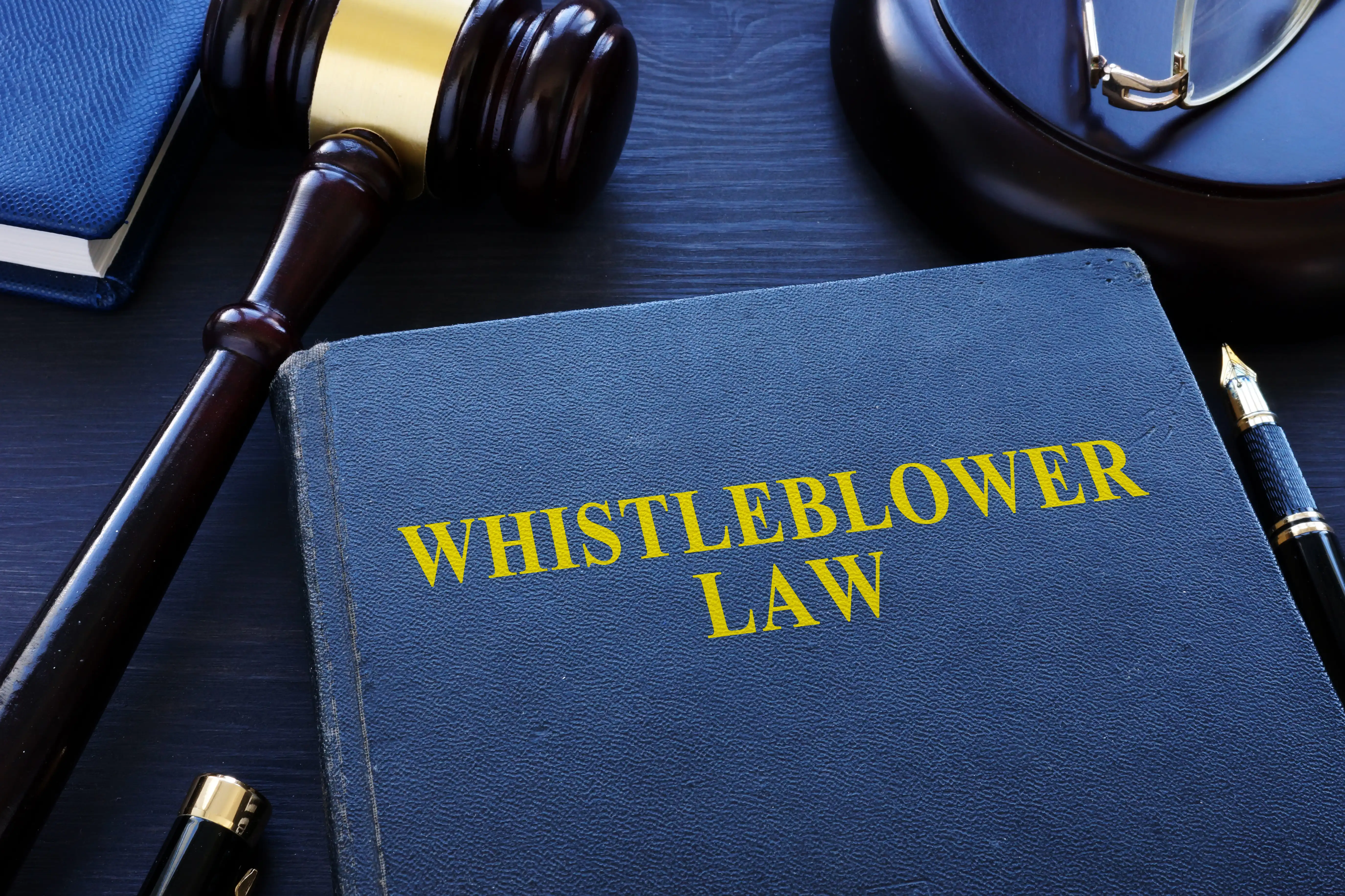 Legal textbook titled Whistleblower Law with a judge's gavel and fountain pen, illustrating employee protections under California Labor Code Section 1102.5