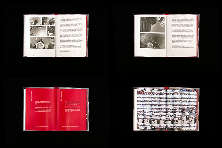 The image shows four open books arranged in a 2x2 grid against a black background. Each book has a red spine and white pages. The top left book displays four black and white photographs arranged in two columns. The top right book contains text. The bottom left book has text on its left page. The bottom right book contains numerous small black and white photographs arranged in columns. All books are open and positioned at various angles.