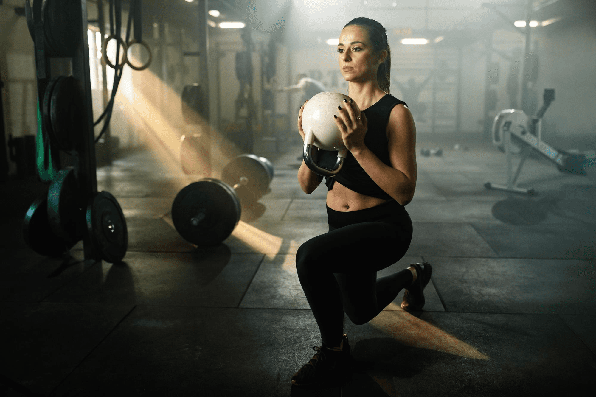 Woman performing forward lunges using a kettlebell.