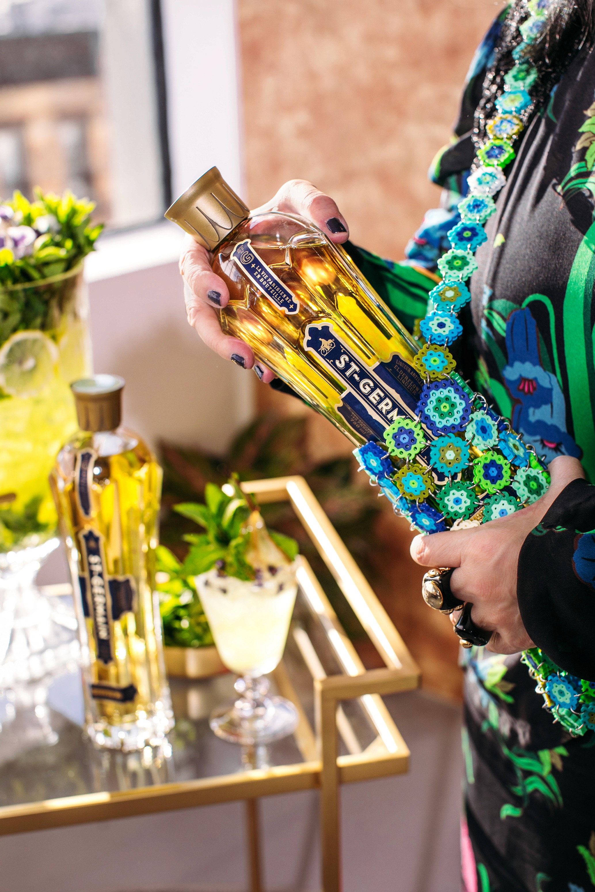 Close detail of Anna Sui holding the St-Germain bottle in its floral tote