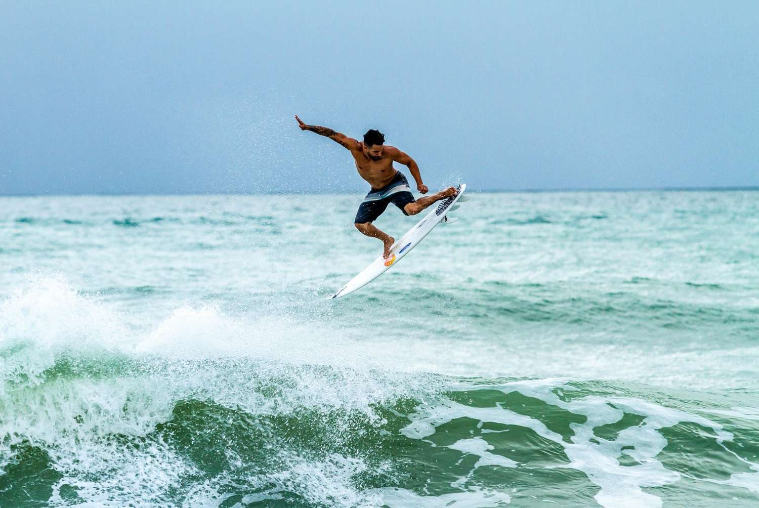 Professional surfer performing an aerial maneuver on a wave — surfboard rental in South America