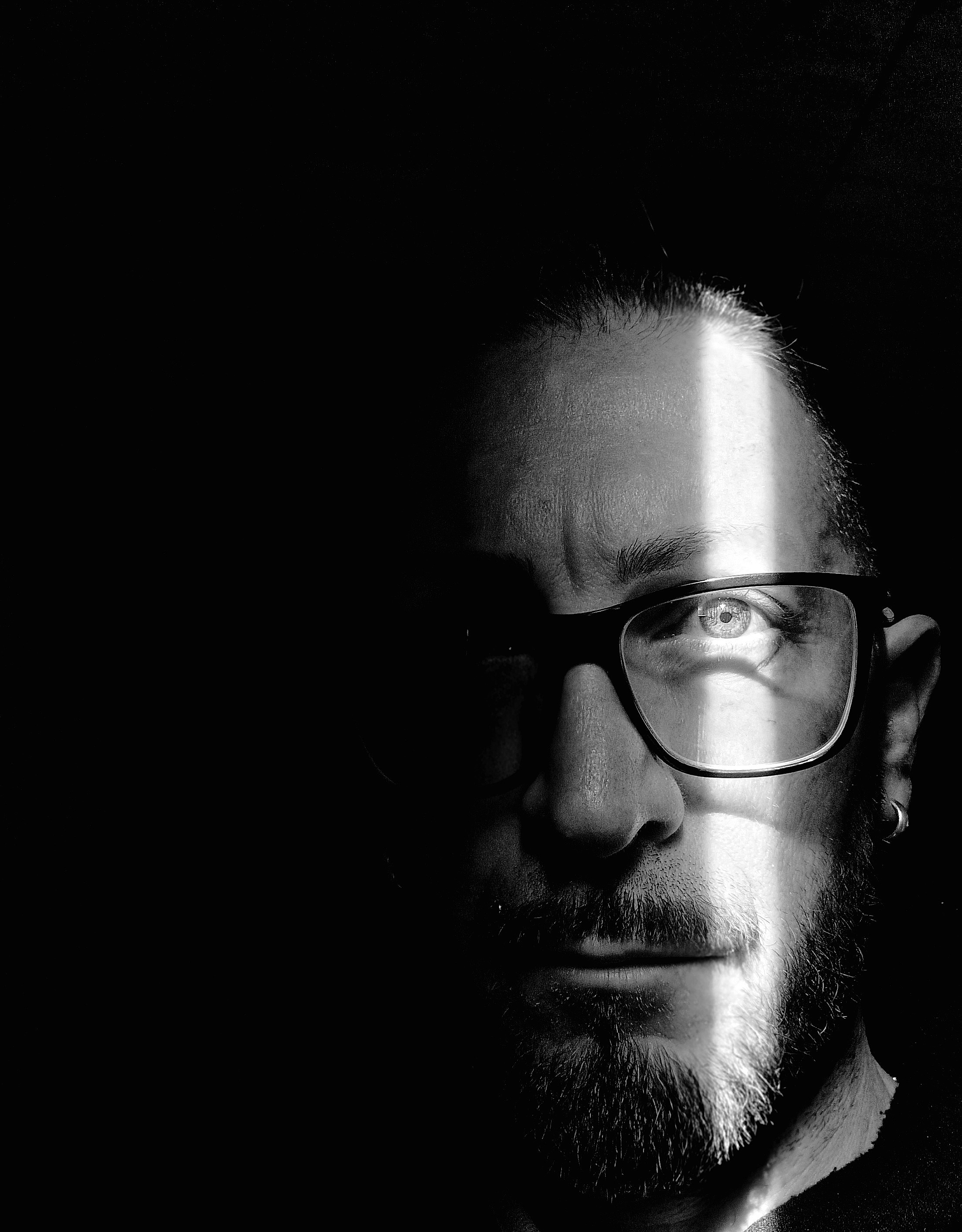 close-up portrait of contemporary artist Mavro in black and white,featuring a sharp light beam across the eye,symbolizing vision and precision.Official contact profile image for Mavro Studio inquiries from collectors and international art galleries.