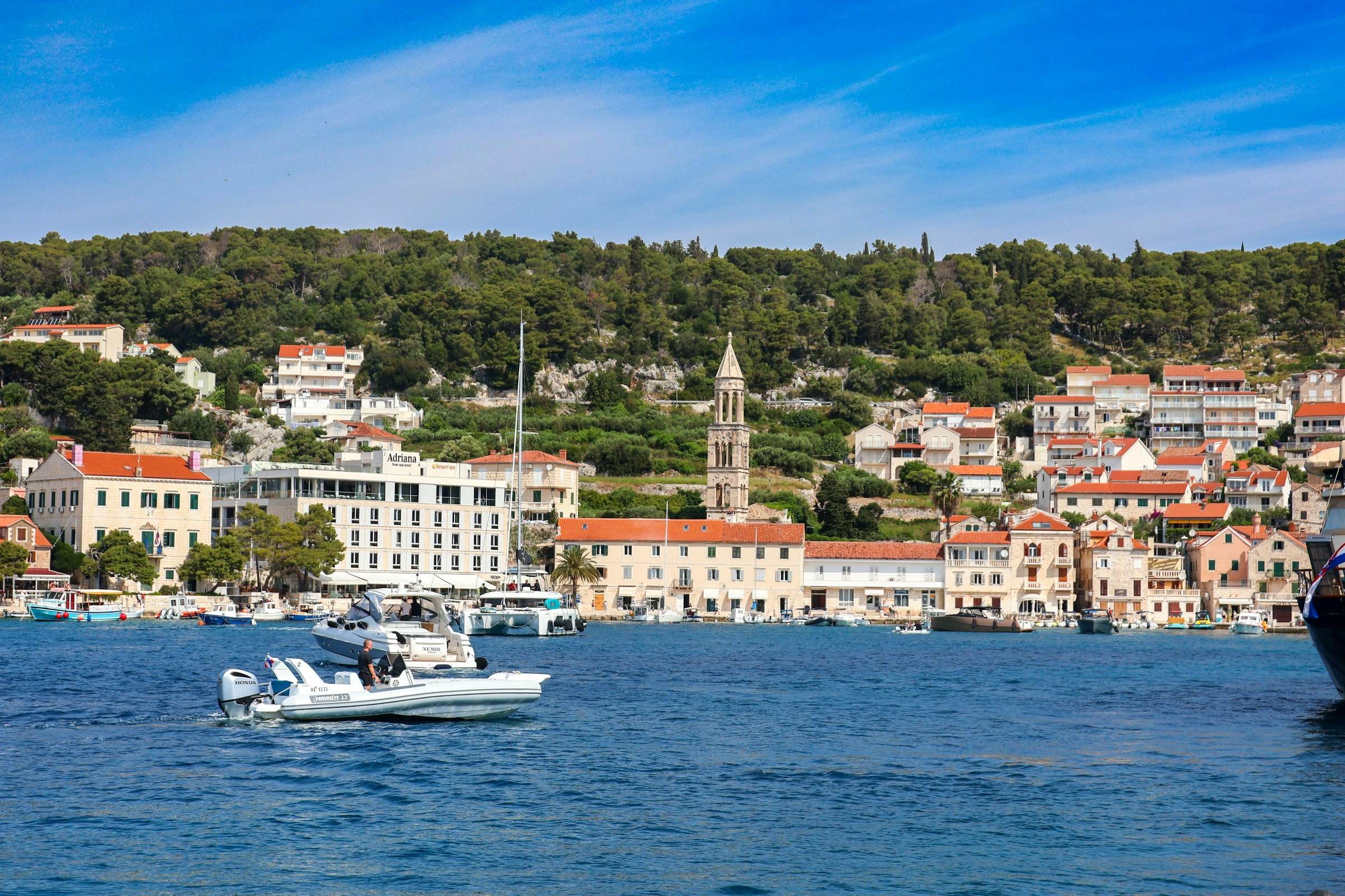 Harbour town with a bell tower, boats and green hills