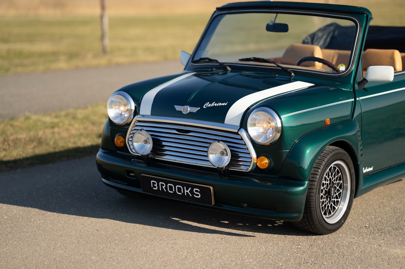 A vintage green convertible car parked on a sunny road, showcasing classic lines and retro details.