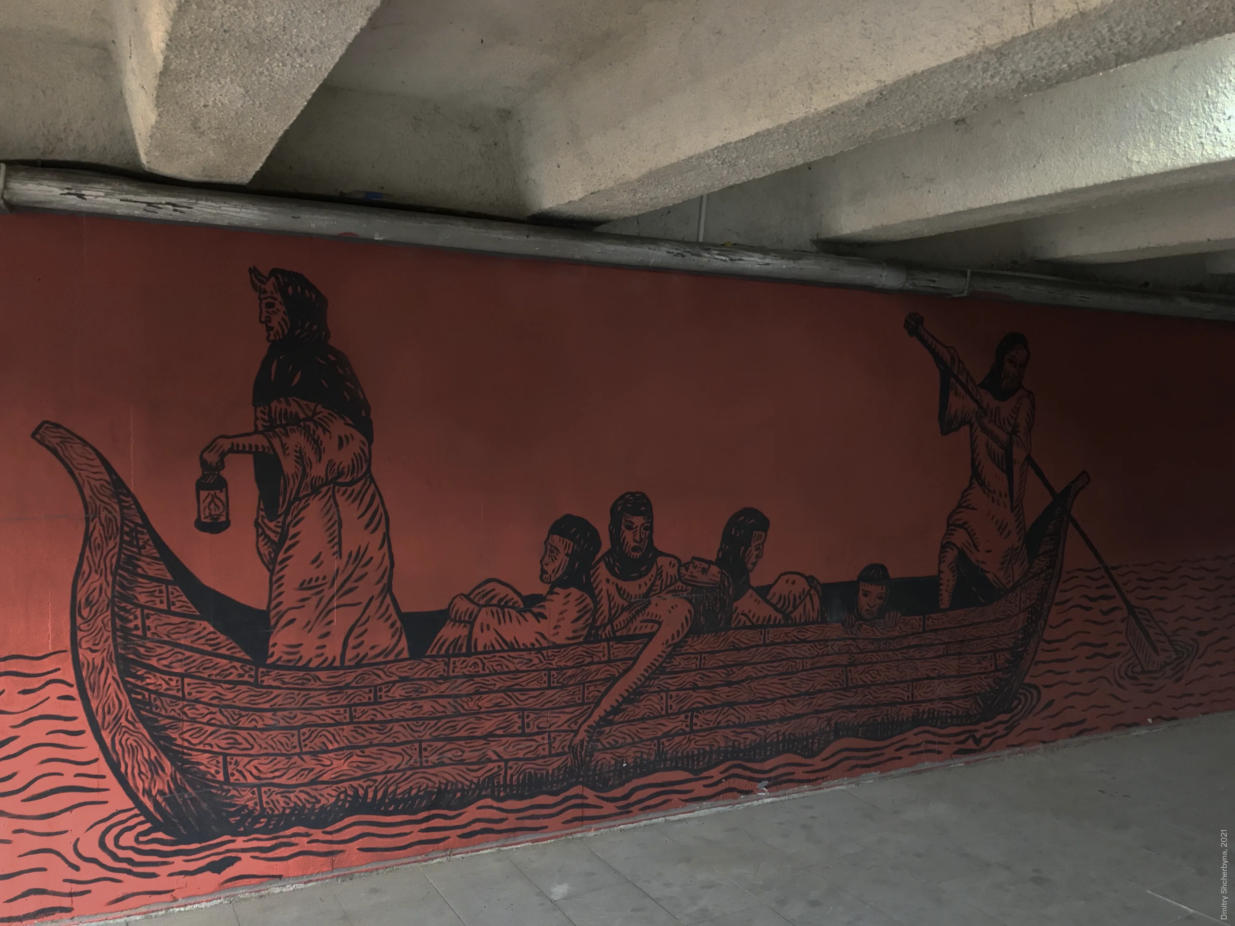 A woodcut-style mural, painted in black on a terracotta background inside an underpass, depicts a long wooden boat carrying several figures across wavy waters. A cloaked figure holds a lantern at the bow and another figure steers the boat with a paddle at the stern.