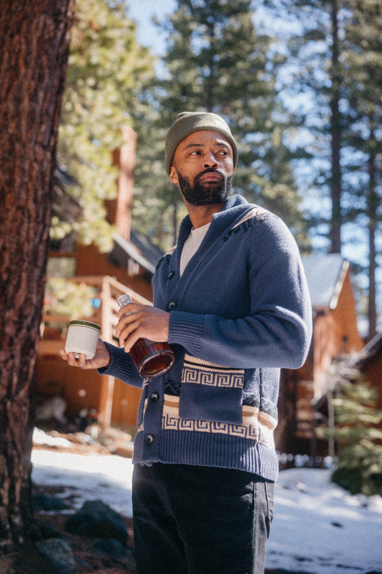 A man standing in the forrest with a mug