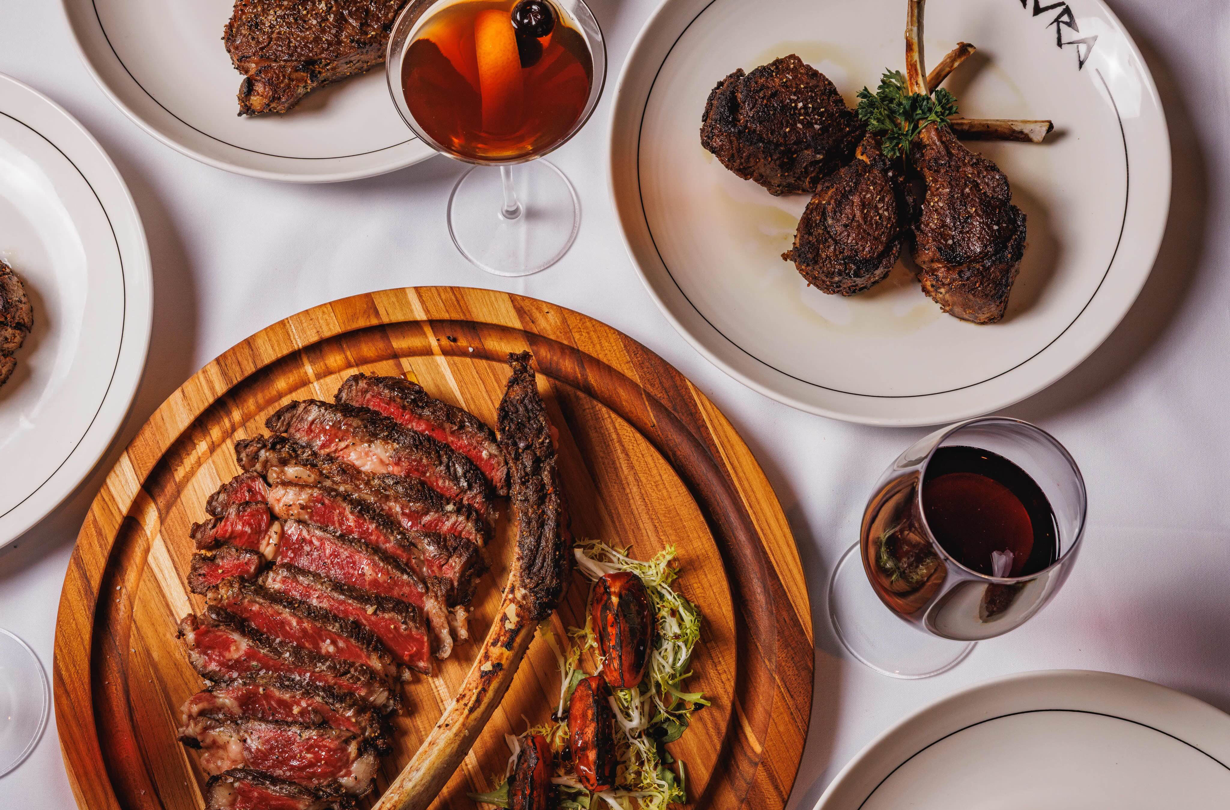 A modern restaurant interior with elegant tables and a large abstract mural on the wall.