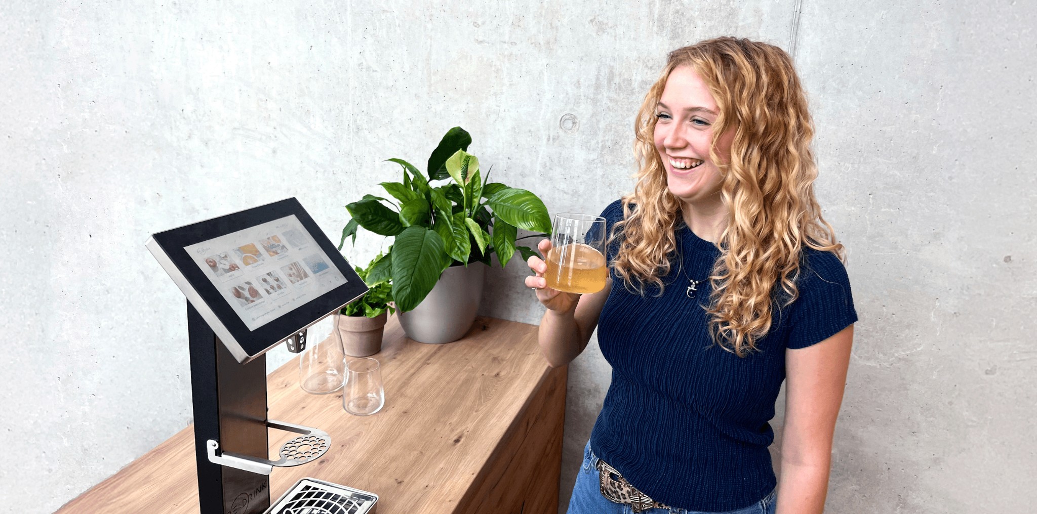 Frau steht am Redrink Dispenser mit einem erfsichenden Getränk ind er Hand