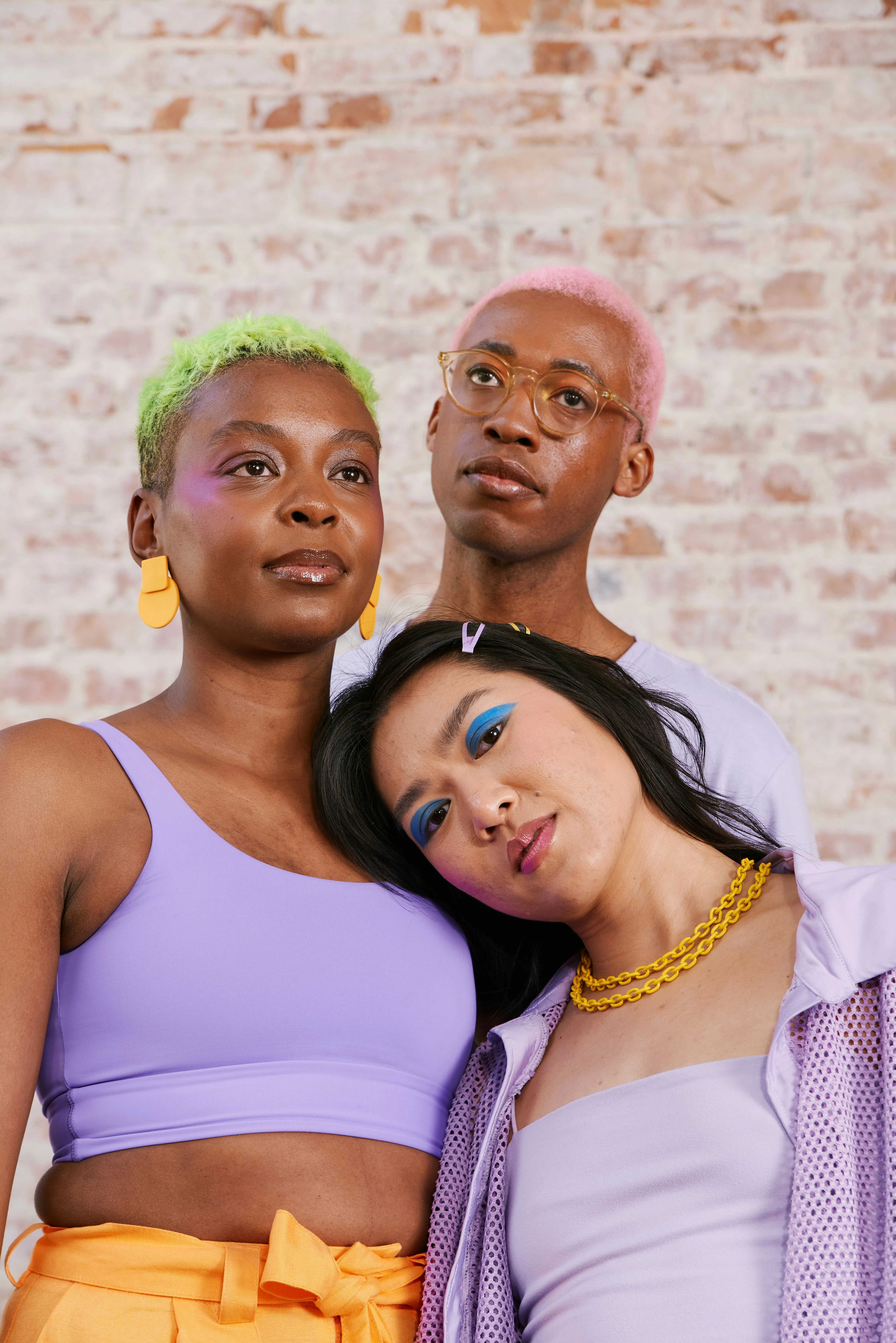 Three queer individuals of diverse backgrounds standing closely together in colorful fashion, symbolizing LGBTQ+ community, inclusion, and belonging.