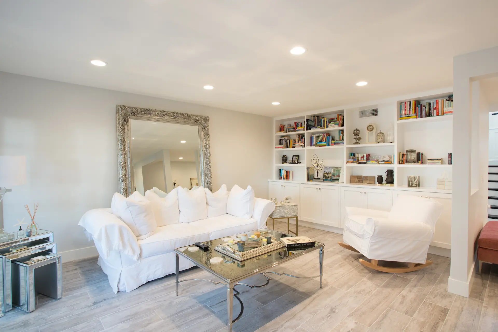Cozy living room with white sofa, armchair, built-in bookshelves, large mirror. From Dana Point Cape Cod remodel, photo by Chris Darnall.
