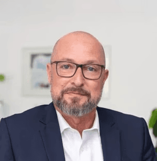 Michael Diehl, Leiter Kooperationen bei der bpa Servicegesellschaft mbH, Portrait eines Mannes mit Brille und grauem Bart im Anzug in einem hellen Büro.