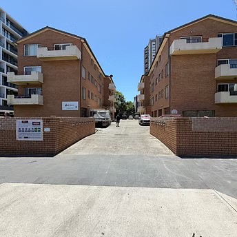 Exterior view of a brick strata apartment complex with a central driveway in a Wollongong suburb