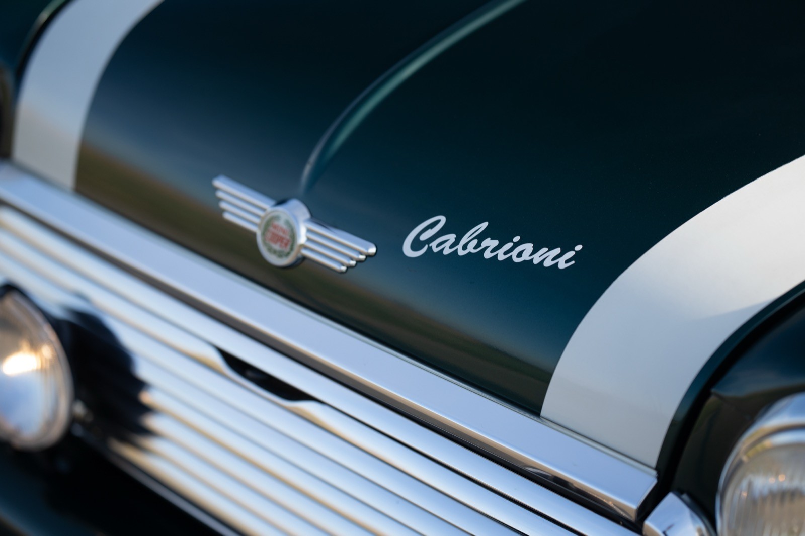 Close-up of a vintage car's badge, displaying the name "Oldsmobile" on a glossy black and silver surface.