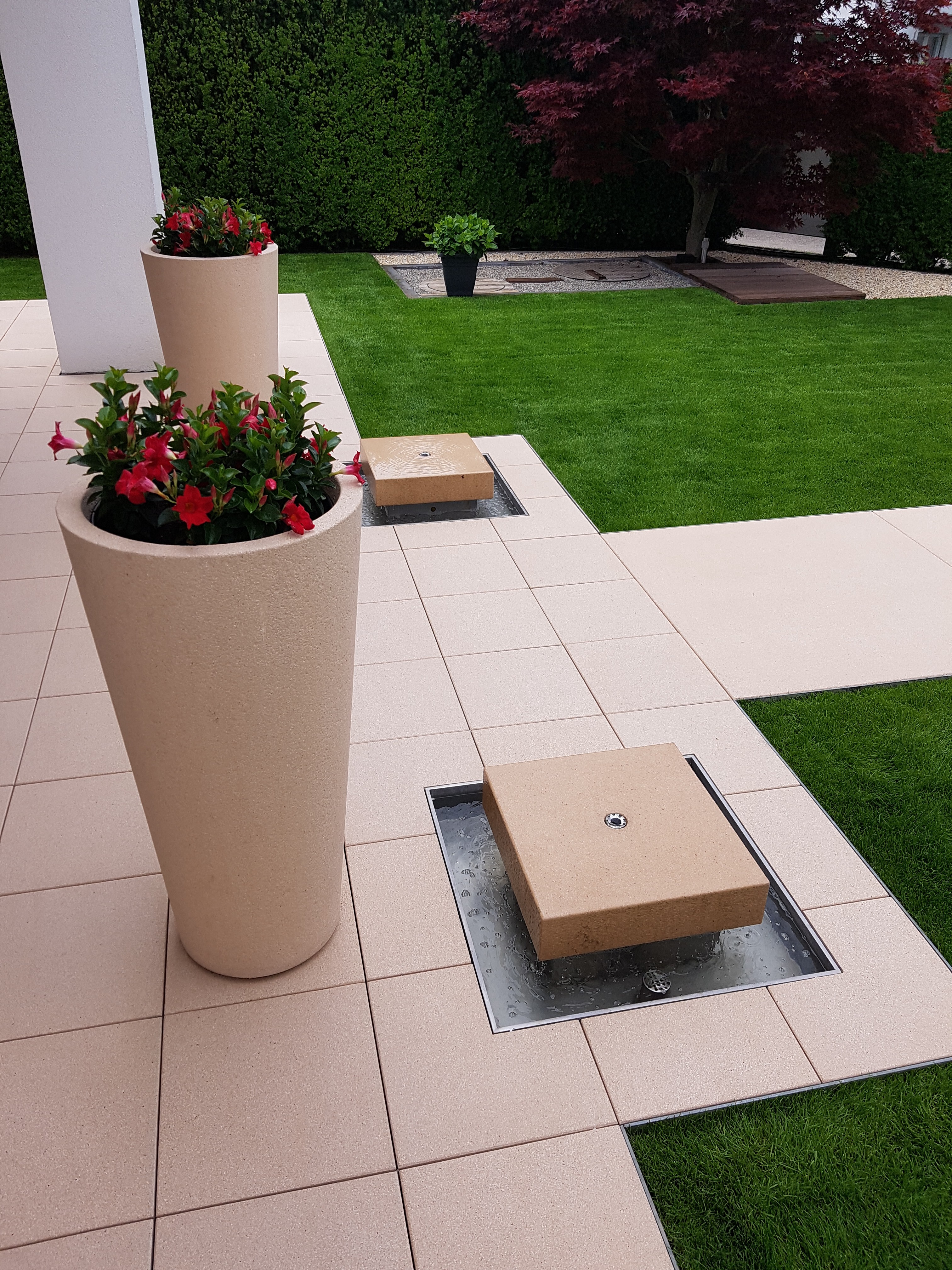 Beige Pflanzkübel mit roten Blumen, integrierte Bodenfontänen im Terrassenbereich, Marohn & Binder Gartenbau und Landschaftsbau. , Marohn & Binder Gartenbau