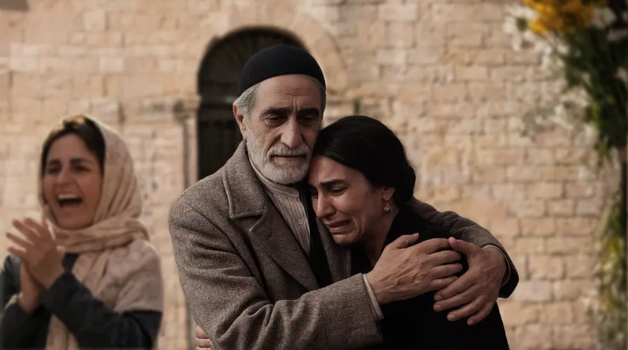 An old man holding a weeping woman while another cries out beside them