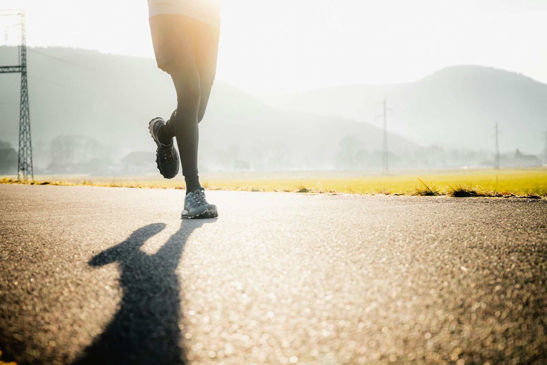 A runner mid-stride on an open road at sunrise.