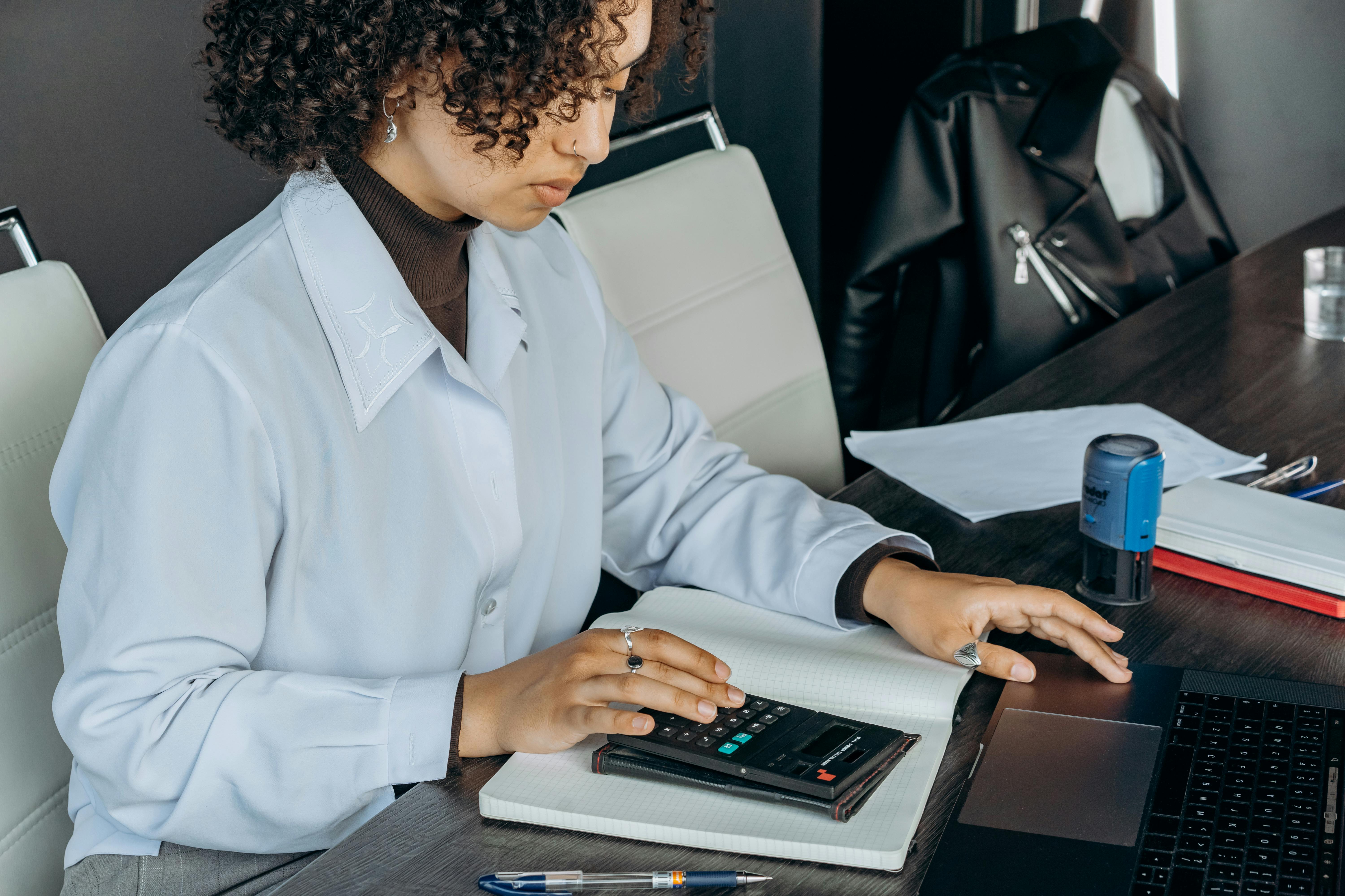 young-woman-in-office-using-a-calculator-for-financial-calculations. - mikhail-nilov (pexels)
