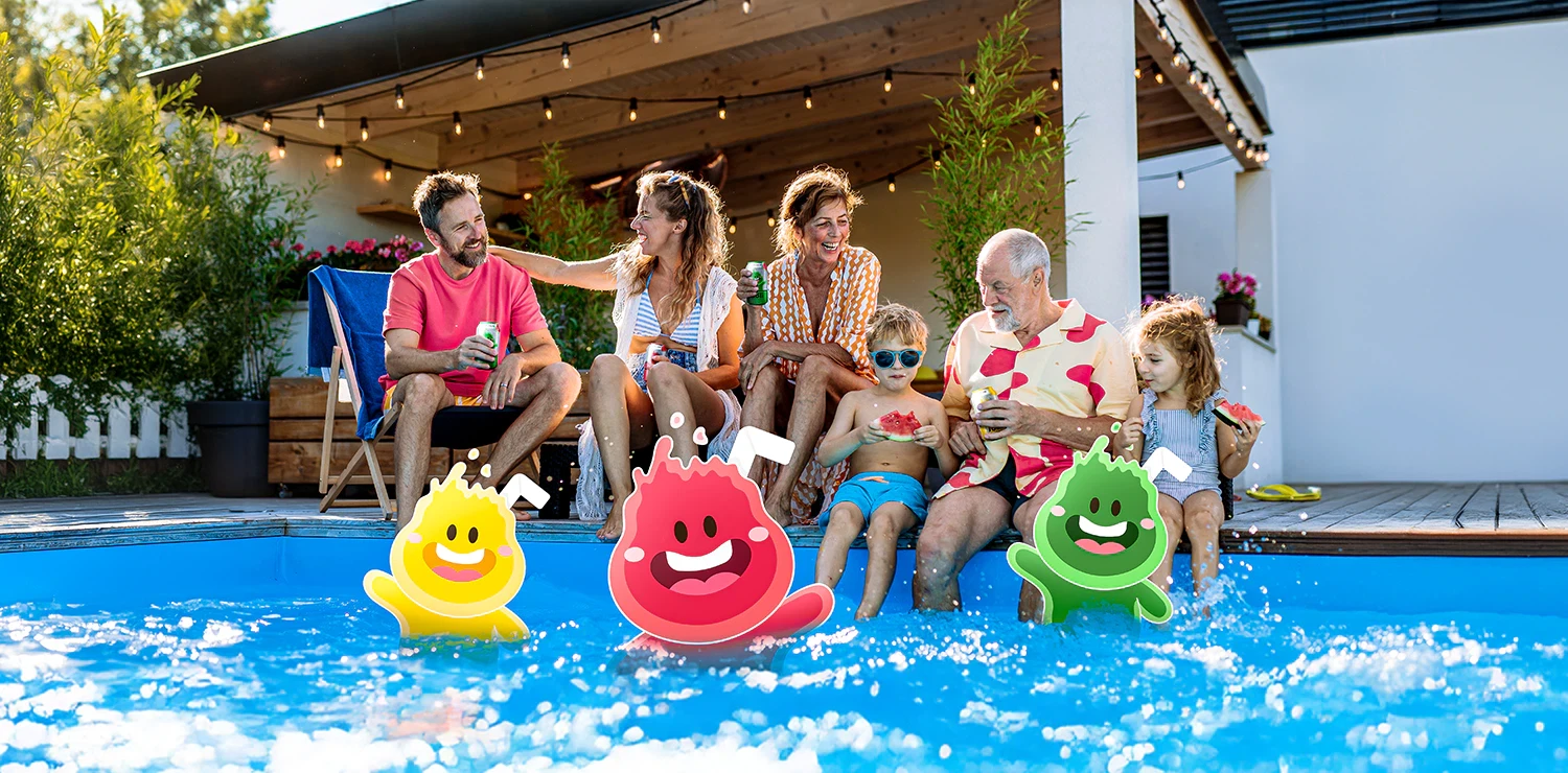 Family and kids enjoying pool party with colorful drink characters and string lights at outdoor patio.
