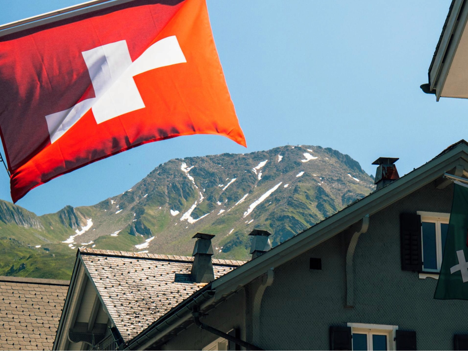 Swiss flag blowing in the wind with a view of the Swiss Alps