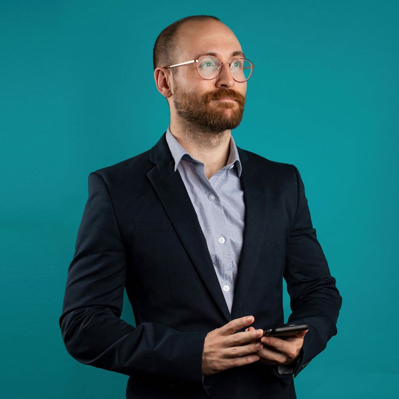 Fotografía de un hombre de mediana edad con lentes y traje formal, con expresión relajada y amable, representando el perfil profesional de un directivo o empresario del sector hospitalidad.