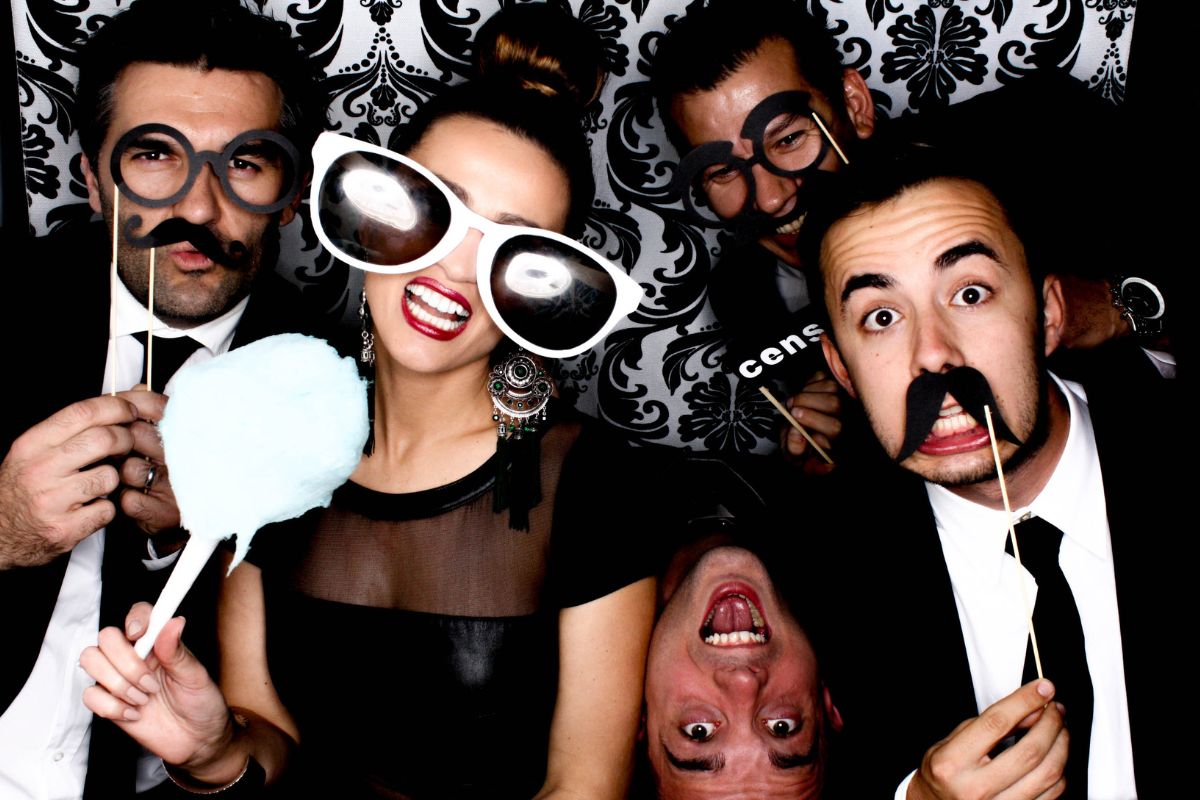 Group of friends wearing funny props in a photo booth.