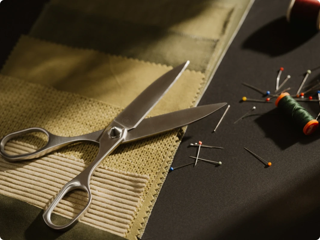 Resharpenable scissors lying on different fabrics, along with needles, yarn, and other DIY tools