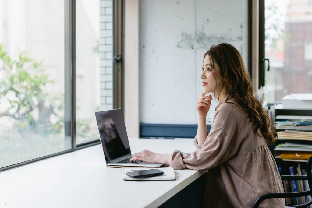 woman thoughtfully reviewing rental property management options on laptop by office window
