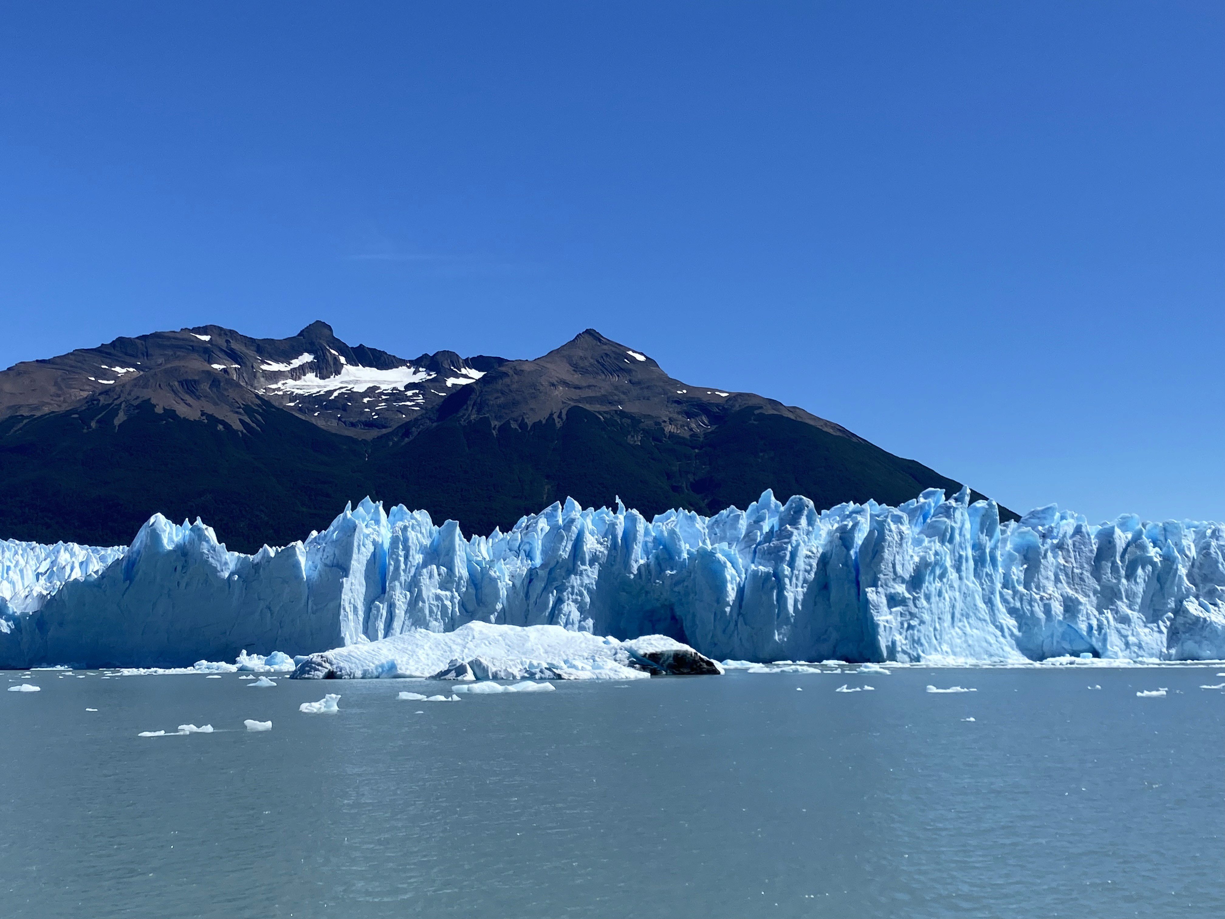 Mujer sentada sobre un tronco frente a una cascada doble en un bosque frondoso de Argentina.