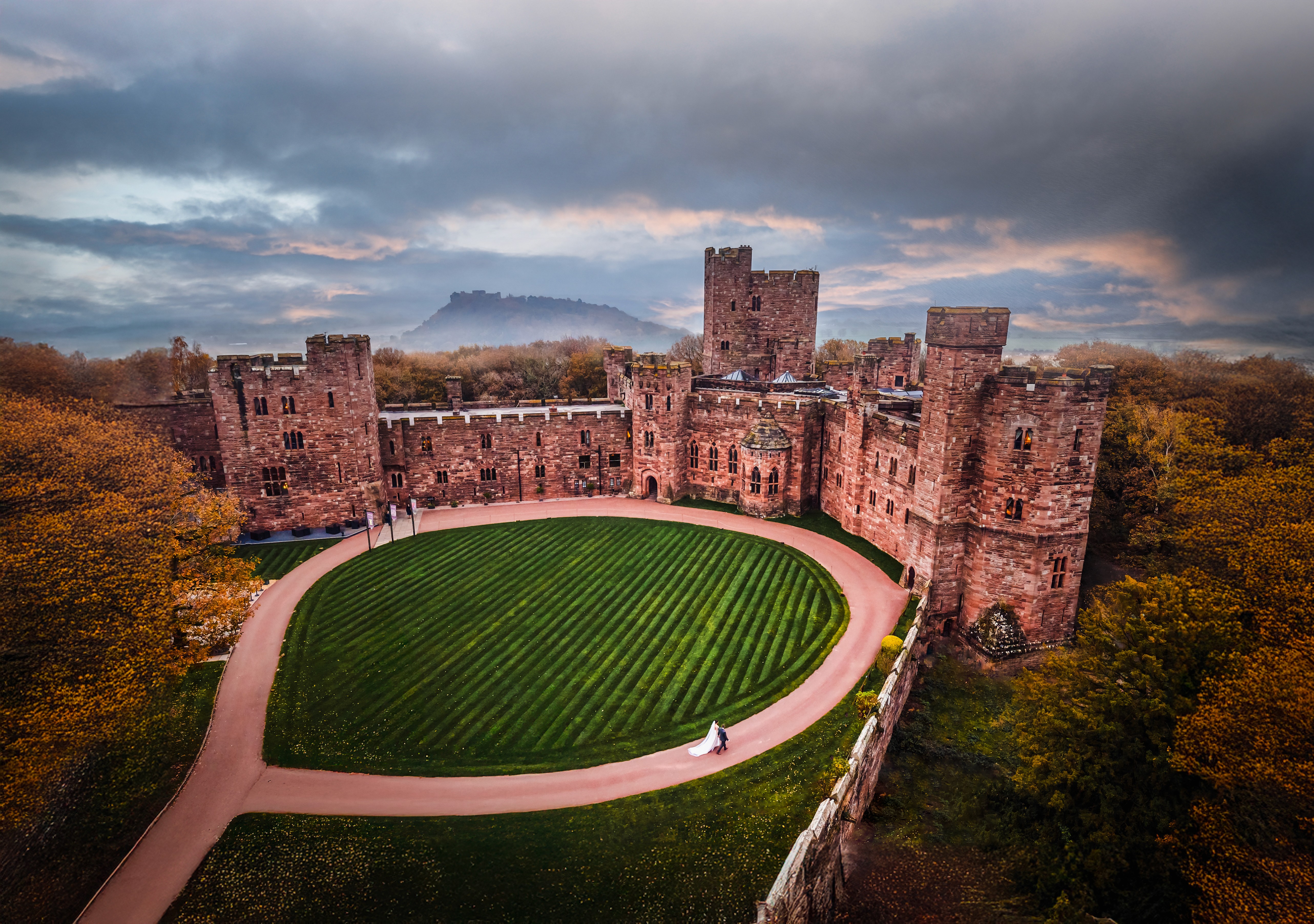 A couple walking along the curved drive beneath Peckforton Castle