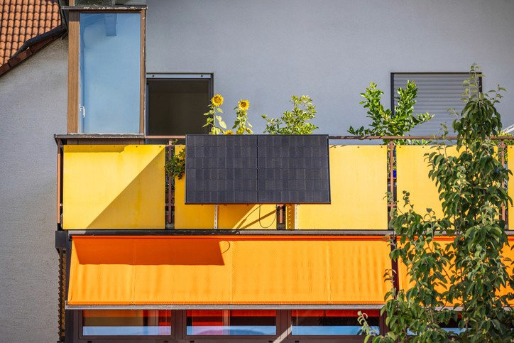 Nahaufnahme eines modernen Balkons mit farbenfrohen Paneelen, Topfpflanzen und einem minimalistischen Design.