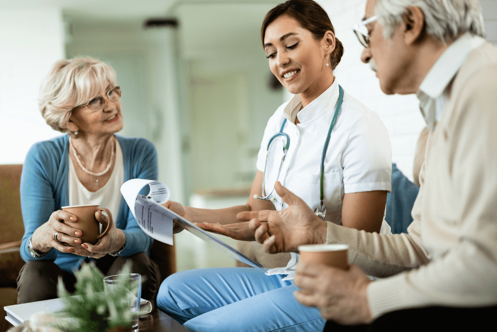 Young healthcare worker and senior couple analyzing medical reports during home visit