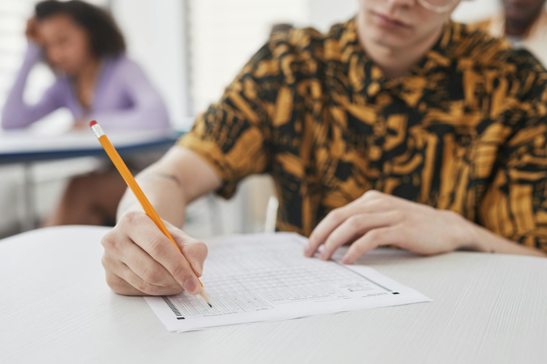 A teacher grading a student's open-ended essay response with a red pen and a detailed scoring rubric.